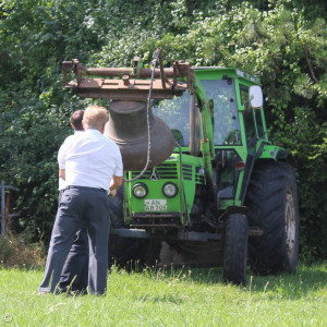 Zwei Männer läuten eine Glocke, die an einem Traktor befestigt ist