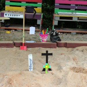 Schatzsuche im Sandkasten mit Kreuz, Kerze und Schaufel